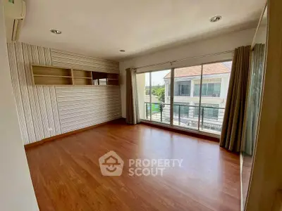 Spacious empty room with large window and wooden flooring, perfect for customization.