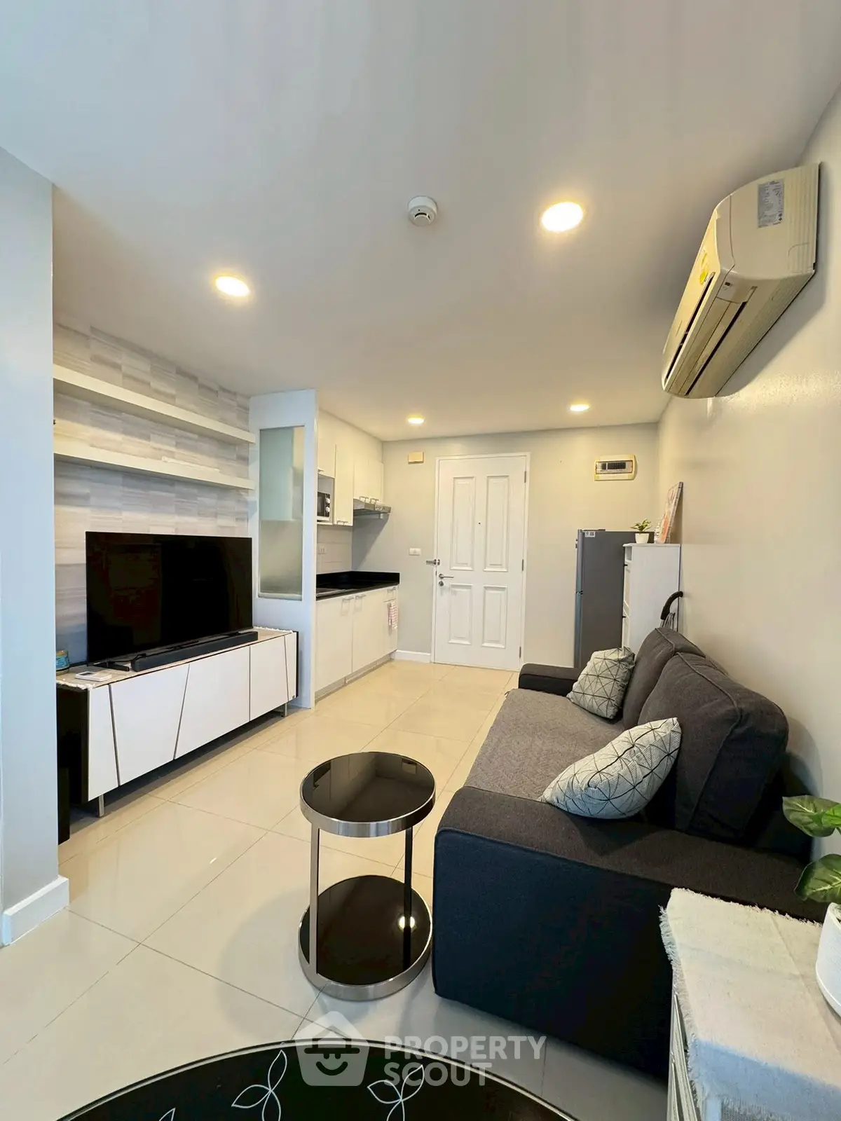 Modern living room with sleek furniture and open kitchen layout, featuring a cozy sofa and stylish decor.