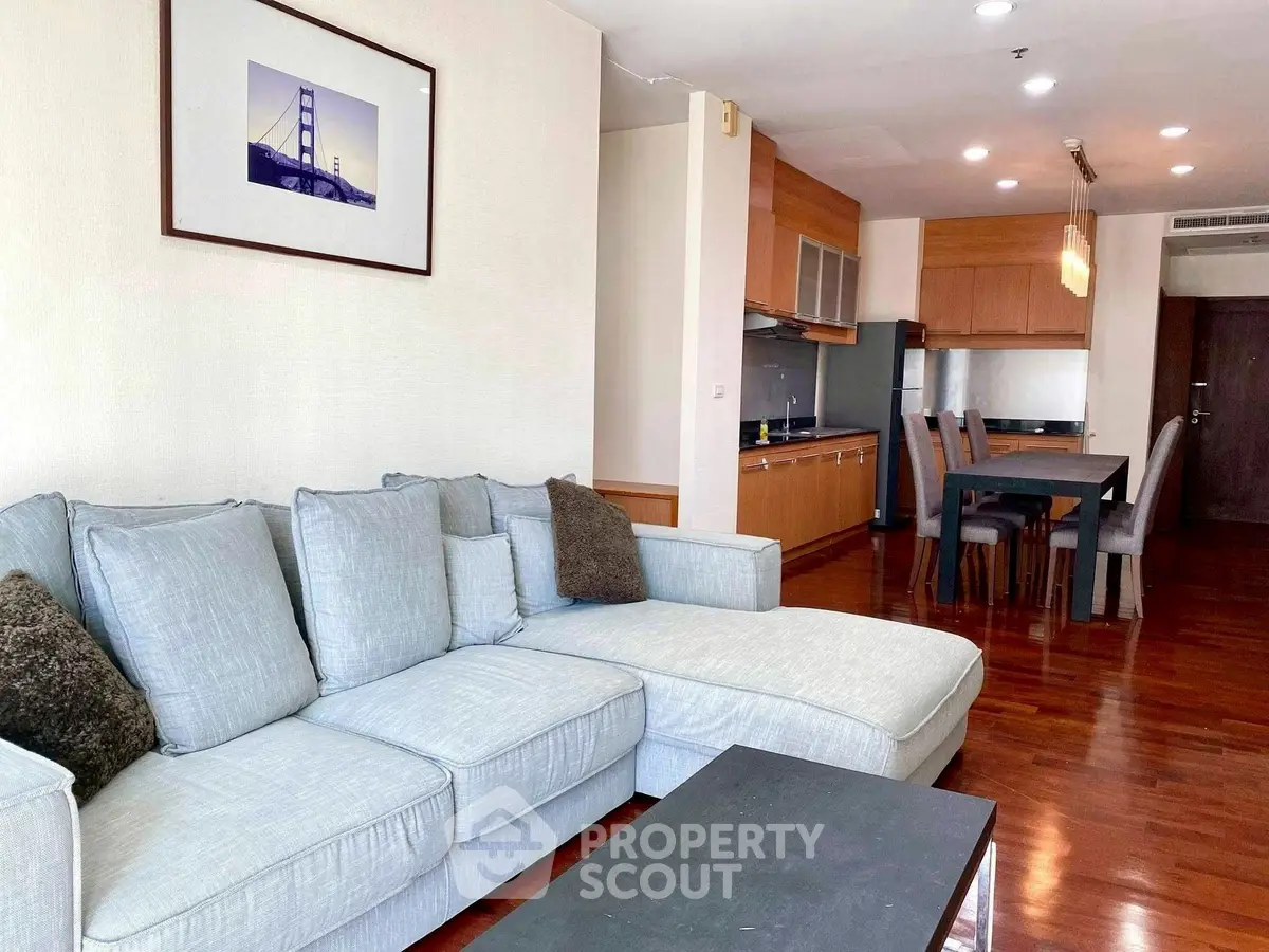 Spacious living room with modern kitchen in open layout, featuring elegant wooden flooring and stylish furniture.