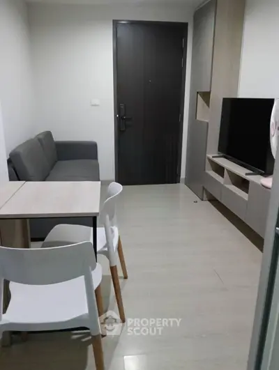 Modern living room with sleek furniture and TV setup in a compact apartment.