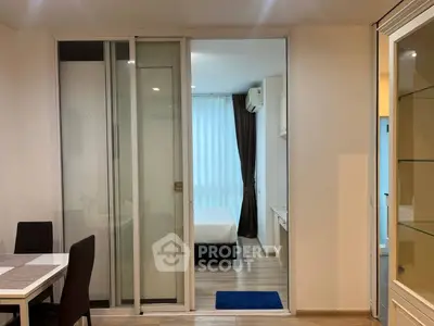 Modern apartment interior with sliding glass doors leading to a cozy bedroom, featuring elegant decor and ample natural light.