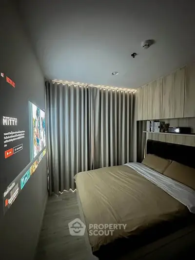 Cozy bedroom with modern decor and built-in storage, featuring a wall projection for entertainment.