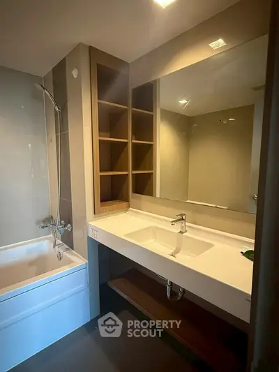 Modern bathroom with sleek sink, bathtub, and wooden shelving.
