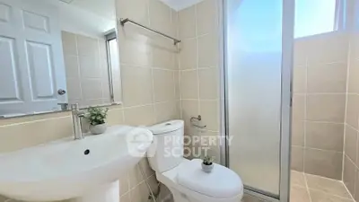 Modern bathroom with sleek fixtures and frosted glass shower in a bright, neutral-toned space.