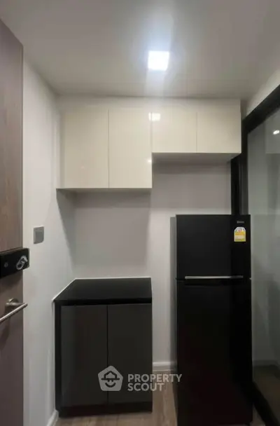 Modern compact kitchen with sleek black fridge and minimalist cabinetry
