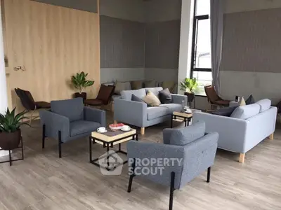 Modern living room with stylish gray sofas and armchairs, wooden flooring, and large windows.