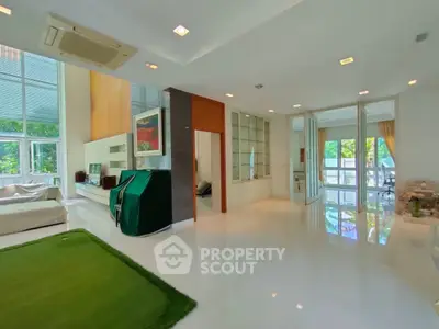 Spacious modern living room with large windows and green accents