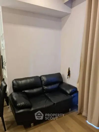 Cozy living room with black leather sofa and elegant curtains, perfect for relaxation.