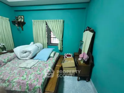 Cozy bedroom with teal walls, floral bedding, and natural light from window.