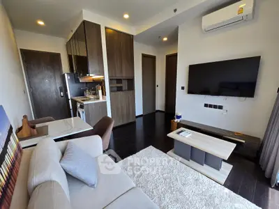 Modern living room with sleek furniture and open kitchen layout, featuring a wall-mounted TV and cozy ambiance.