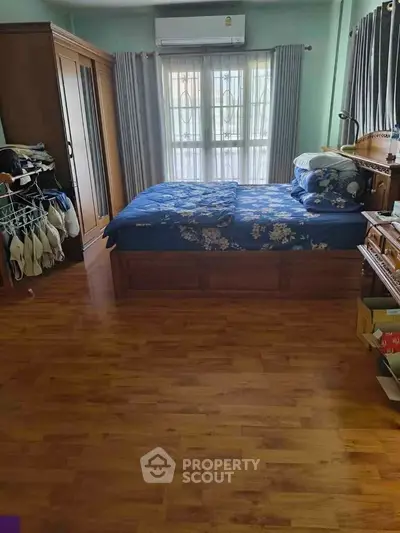 Cozy bedroom with wooden flooring and large window for natural light.