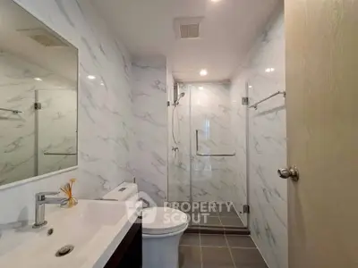 Modern bathroom with marble walls and glass shower enclosure