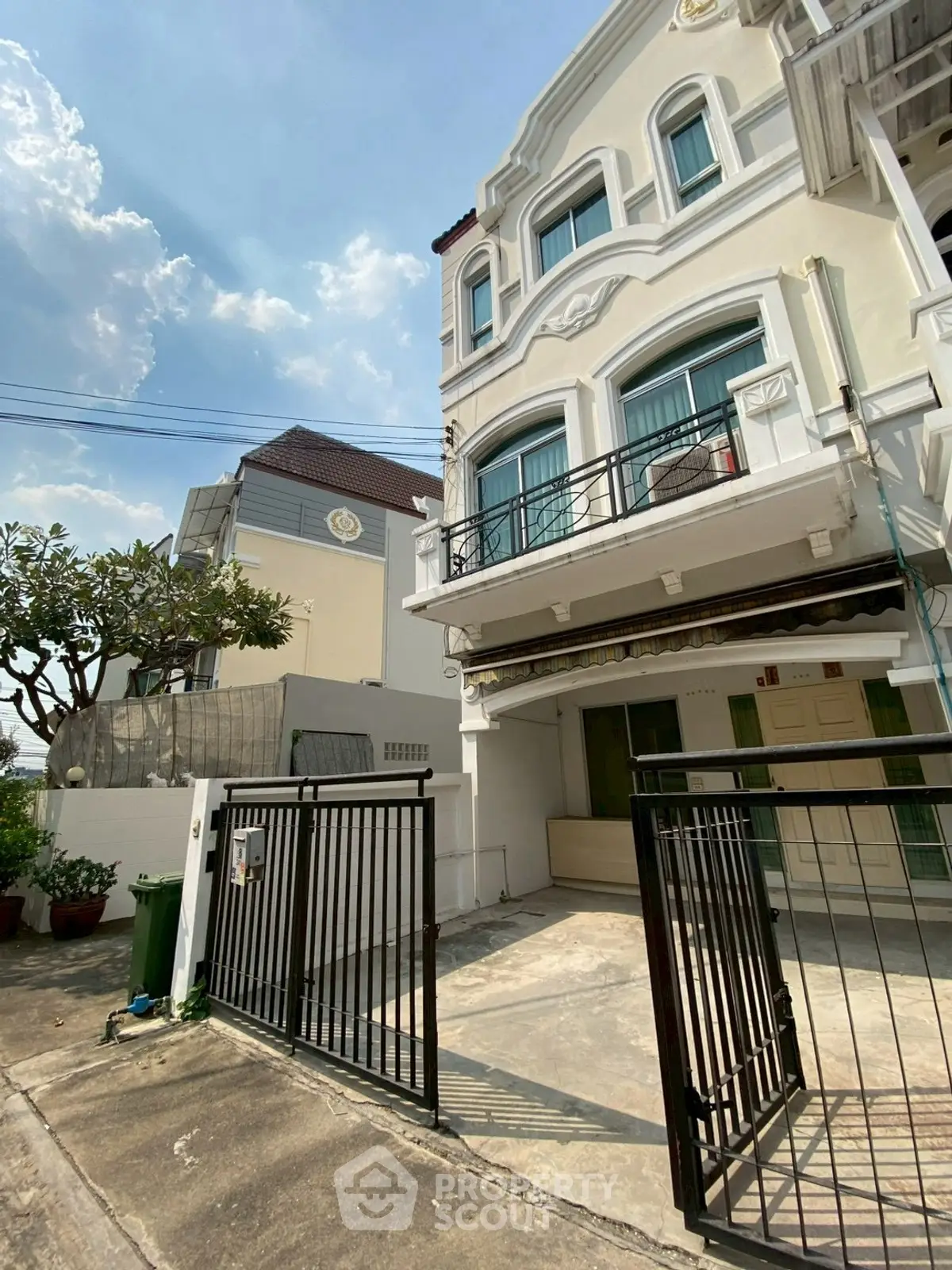 Charming three-story townhouse with gated entrance and balcony, perfect for family living in a serene neighborhood.