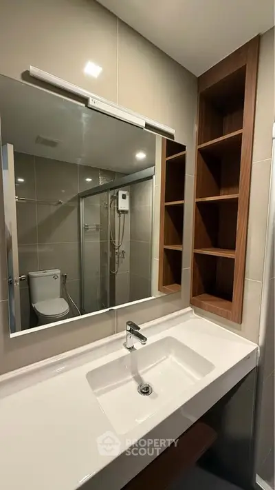 Modern bathroom with sleek sink, mirror, and shower in contemporary design.