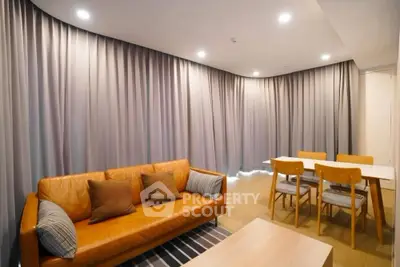 Modern living room with leather sofa and dining area, featuring elegant lighting and stylish decor.