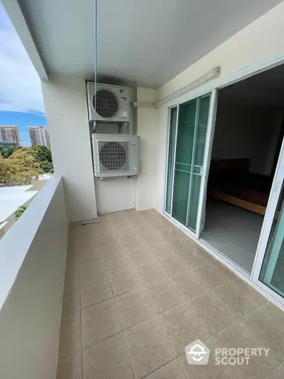 Spacious balcony with sliding doors and air conditioning units, offering urban views.