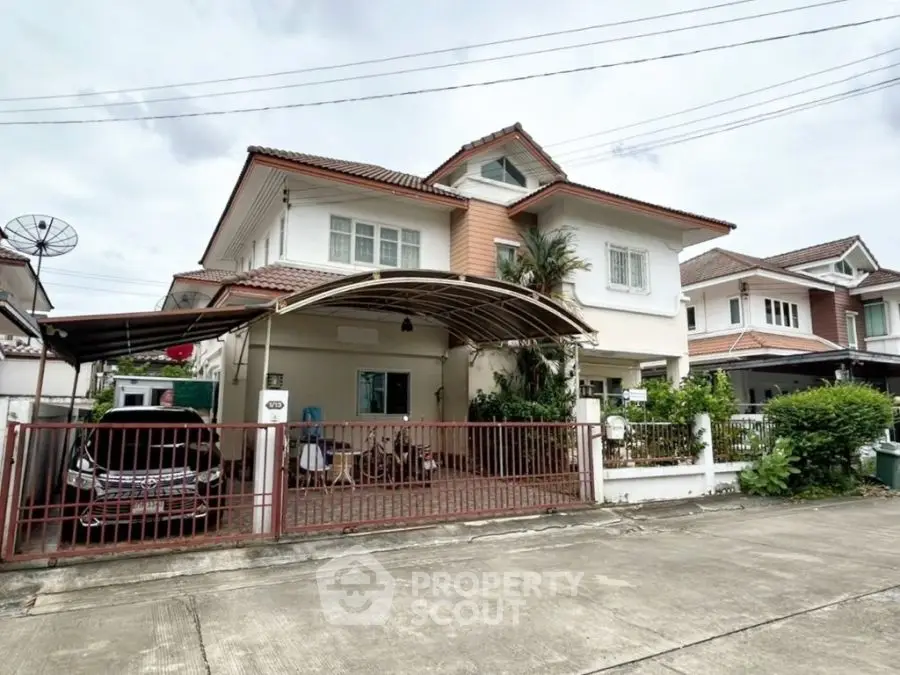 Charming two-story house with carport and lush greenery in a serene neighborhood.
