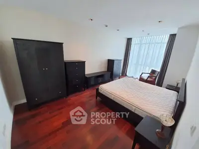 Spacious bedroom with elegant dark wood furniture and large window for natural light.