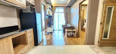 Modern open-plan apartment with stylish kitchen and cozy living area, featuring wooden flooring and ample natural light.
