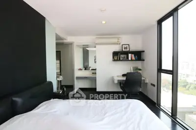 Modern bedroom with sleek design and city view, featuring a workspace and large windows.