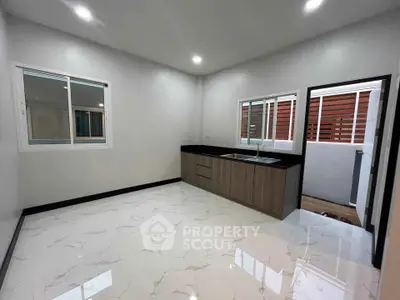 Modern kitchen with sleek cabinetry and marble flooring in a new home.
