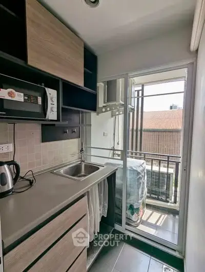 Compact kitchen with balcony access and modern appliances in urban apartment