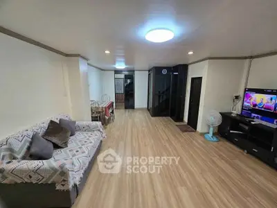 Spacious living room with modern decor and wooden flooring, featuring a cozy sofa and entertainment setup.