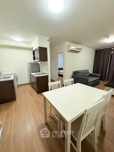 Modern open-plan living room and kitchen with stylish furniture and wooden flooring.