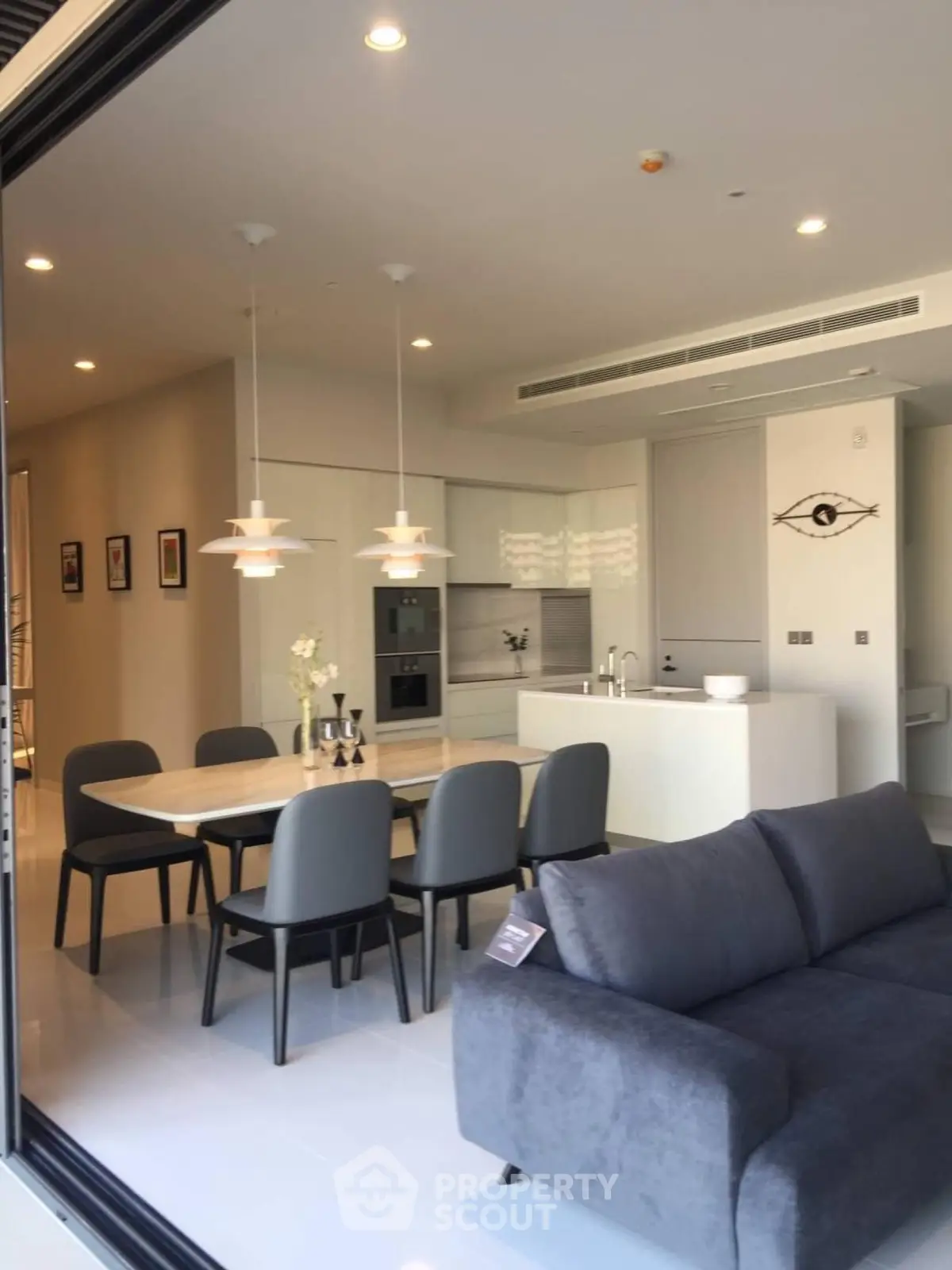 Modern open-plan living room and kitchen with sleek furniture and elegant lighting.