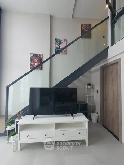 Modern living room with stylish staircase and sleek TV setup in a contemporary apartment.