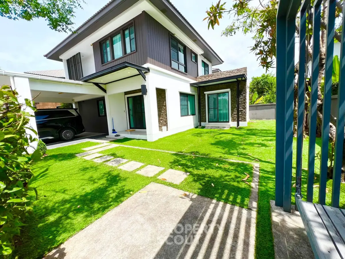 Modern two-story house with lush green lawn and carport in a serene neighborhood.