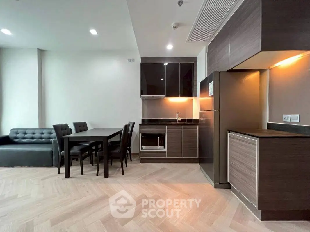 Modern open-layout kitchen with sleek cabinetry and dining area in stylish apartment.