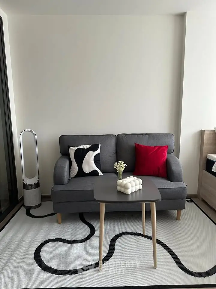 Modern living room with stylish gray sofa, artistic rug, and elegant decor accents.