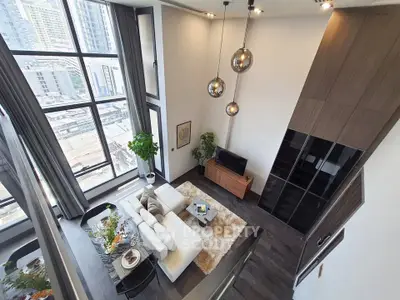Stunning high-ceiling living room with large windows and modern decor in urban apartment.