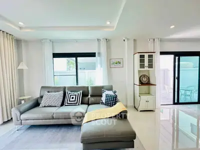 Modern living room with stylish gray sofa and large windows offering natural light.