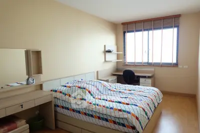 Spacious bedroom with modern furniture and large window for natural light.