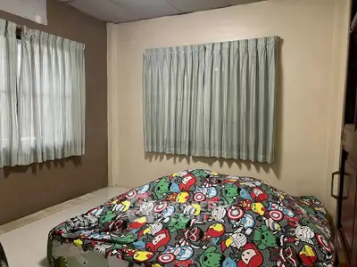 Cozy bedroom with superhero-themed bedding and large windows with curtains.