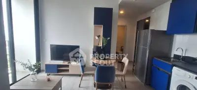Modern apartment interior with stylish blue accents, featuring a cozy living area and kitchen with appliances.