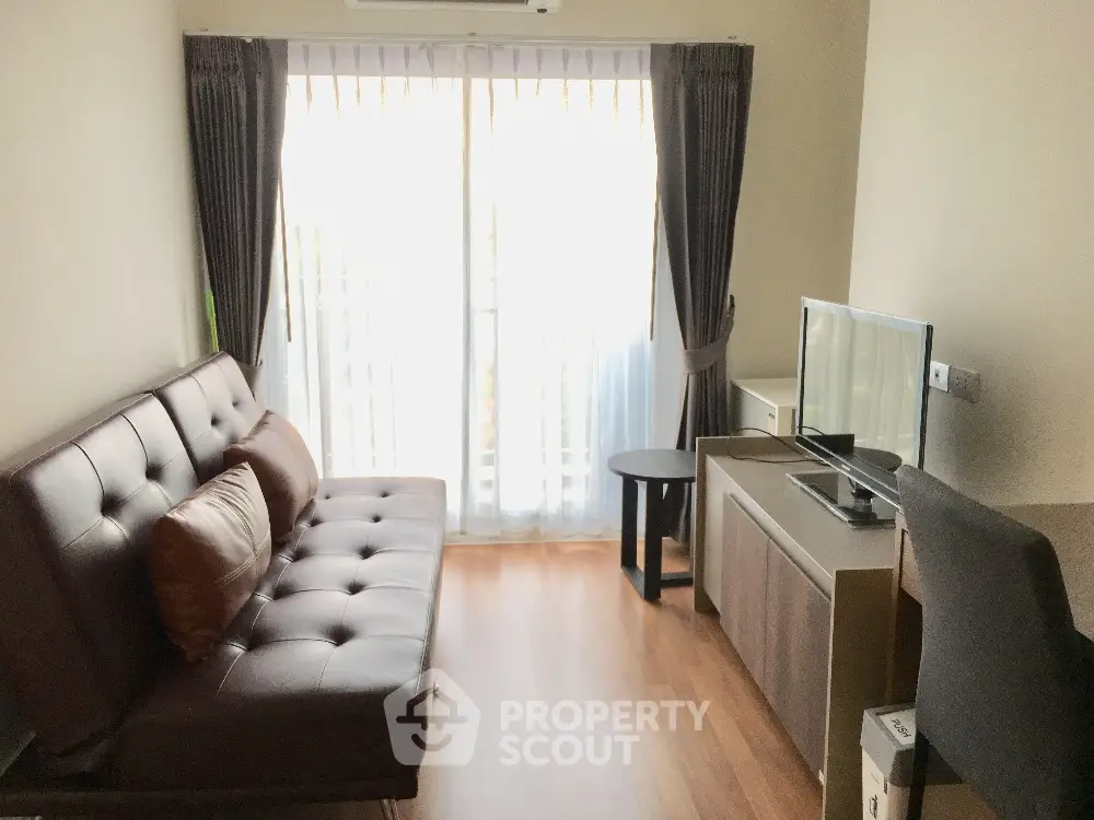Cozy living room with modern sofa and TV, natural light through large window