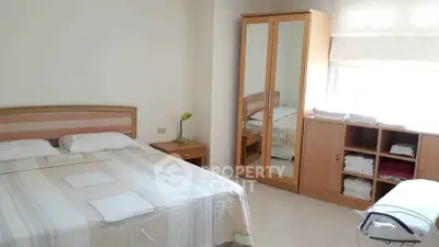 Spacious bedroom with ample natural light, large bed, mirrored wardrobe, and a cozy study area, perfect for relaxation and productivity.