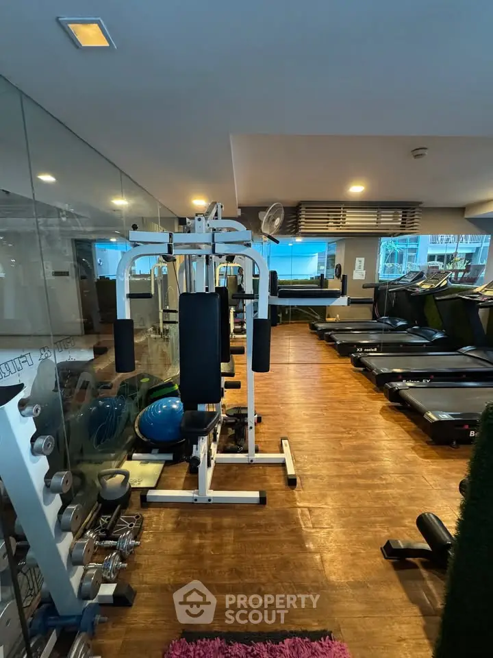 Modern gym with state-of-the-art equipment and wooden flooring in a residential building.