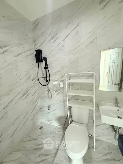 Modern bathroom with marble tiles and compact fixtures for efficient space use.