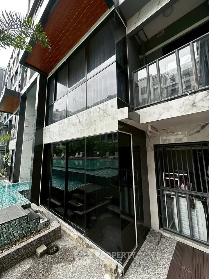 Modern building exterior with poolside view and sleek architectural design.