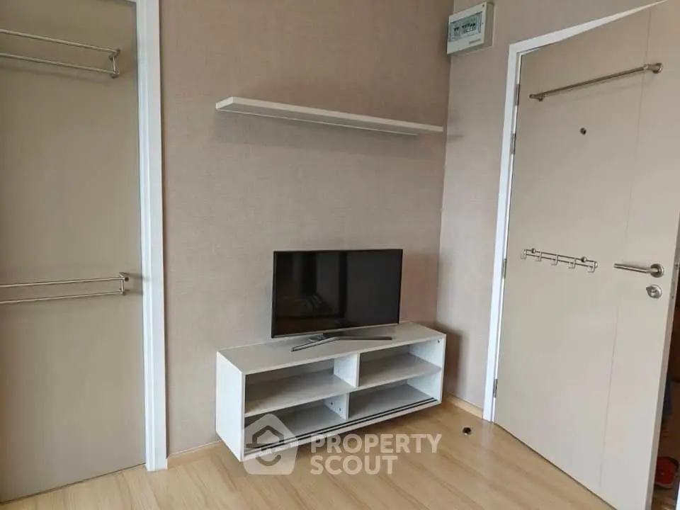 Modern living room with sleek TV stand and wall shelf, featuring minimalist design and light wood flooring.
