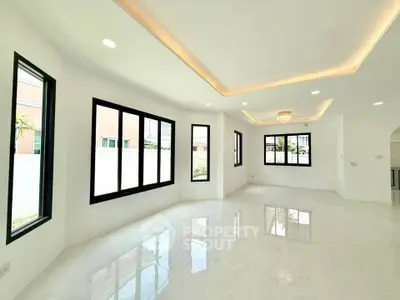 Spacious modern living room with large windows and elegant lighting, perfect for natural light lovers.