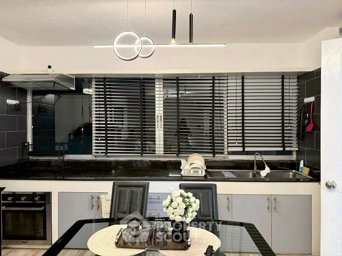 Modern kitchen with sleek black countertops and stylish lighting fixtures.