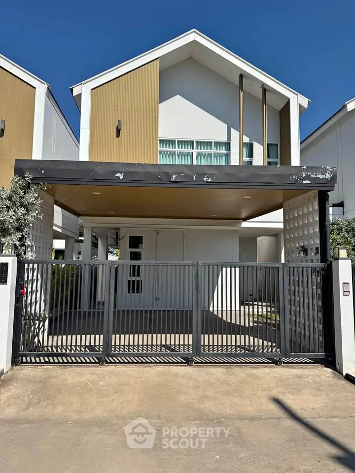 Modern two-story house with gated entrance and contemporary design in a sunny neighborhood.