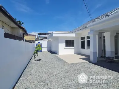 Spacious and modern single-level home with a large driveway and white exterior walls, under a clear blue sky, offering a serene suburban living experience.