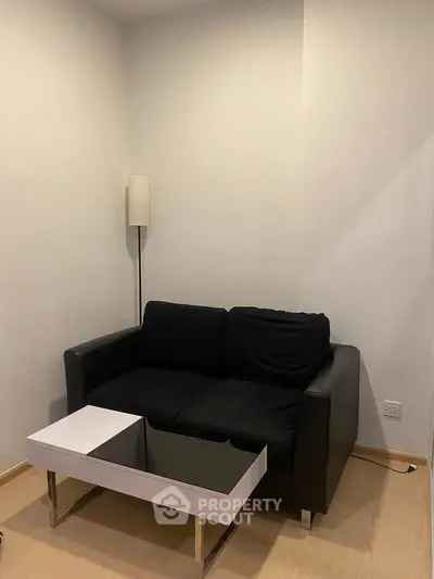 Cozy living room with modern black sofa and sleek coffee table, perfect for relaxation.