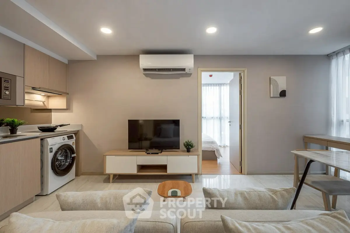 Modern living room with open kitchen and washing machine, cozy and stylish interior design.